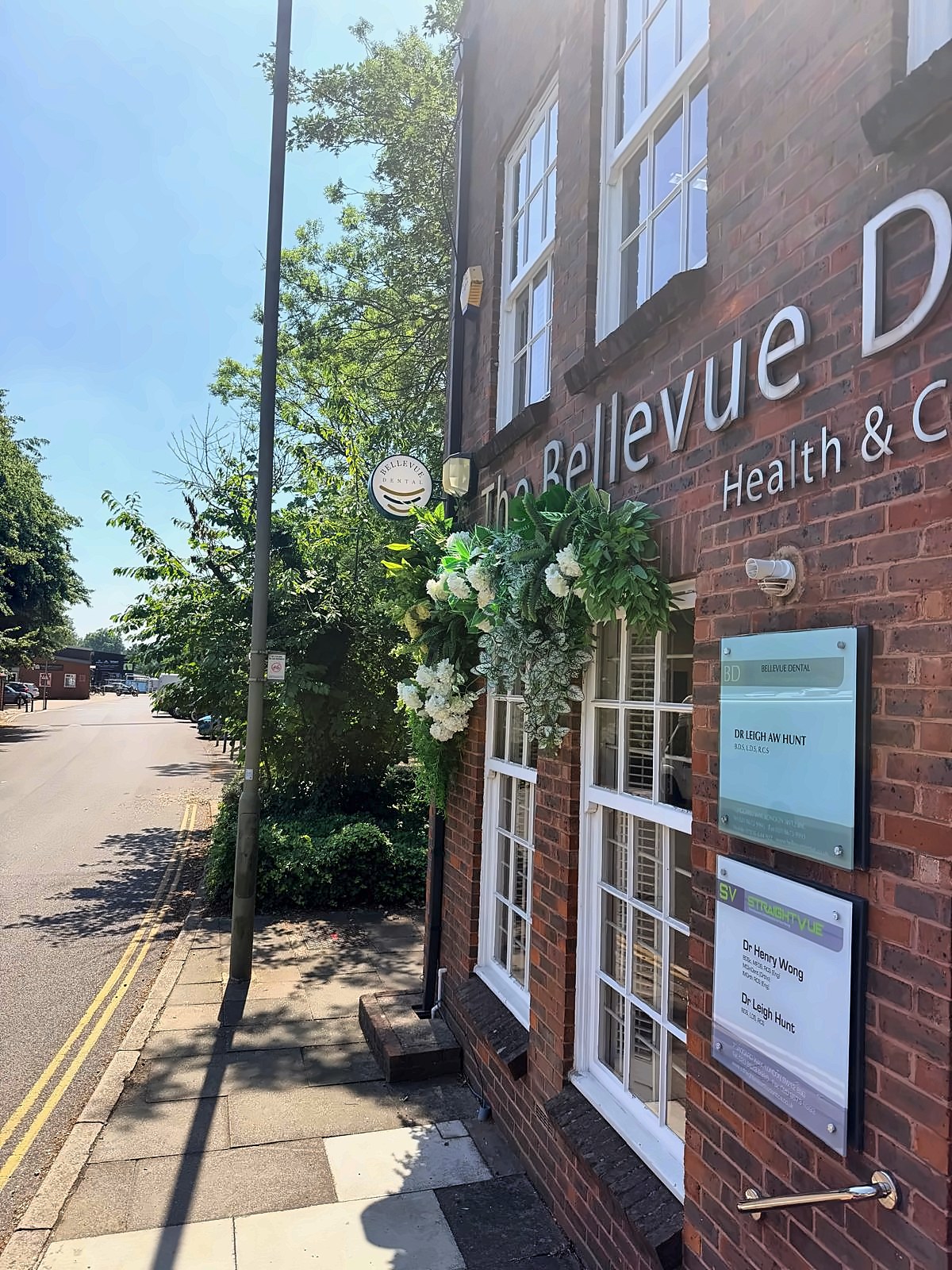 The front of Bellevue Dental on Jaggard Way, next to Wandsworth Common station, with its floral arch and hanging sign