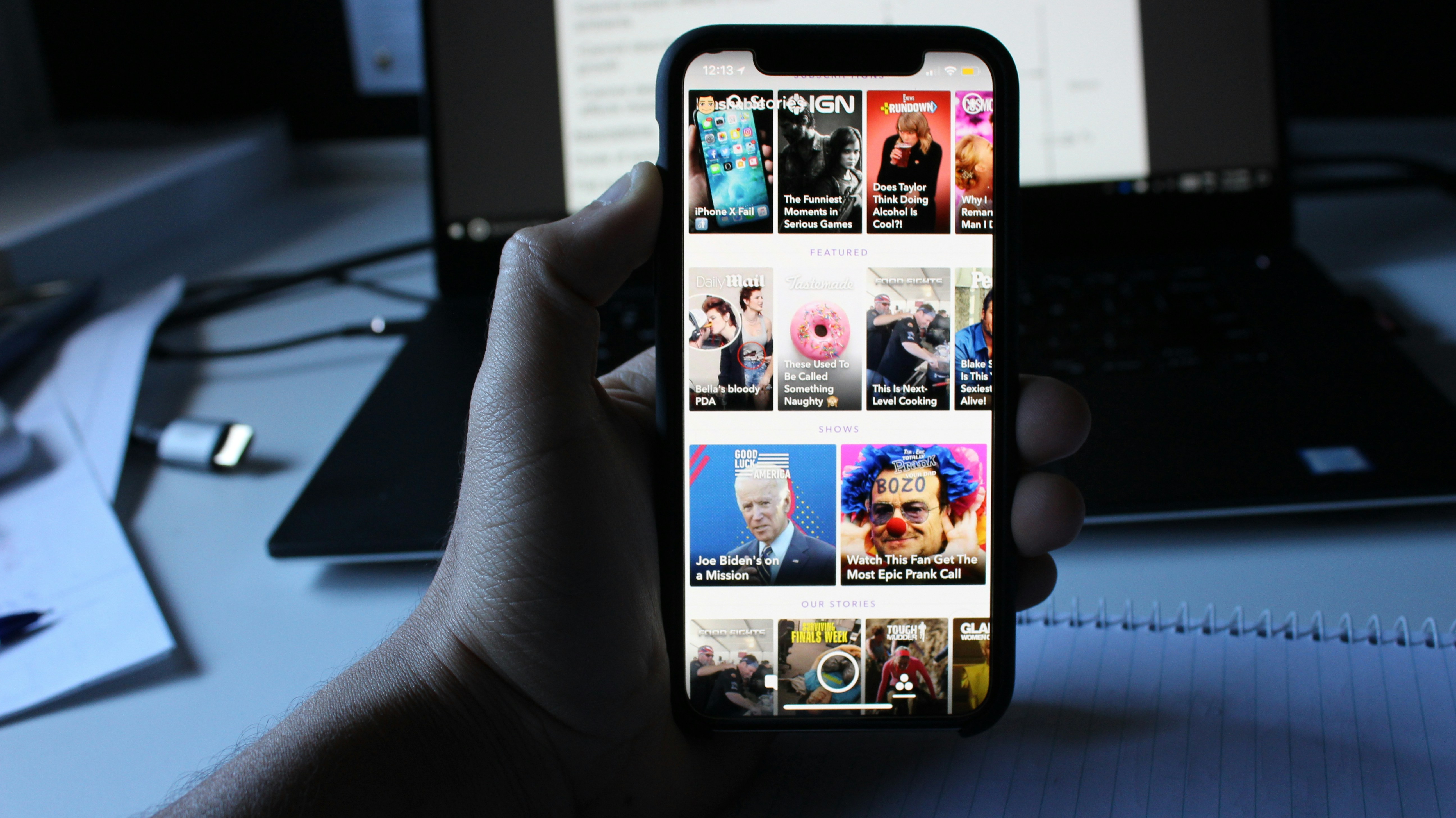 a hand holding a mobile phone, the screen is showing multiples articles of the latest news