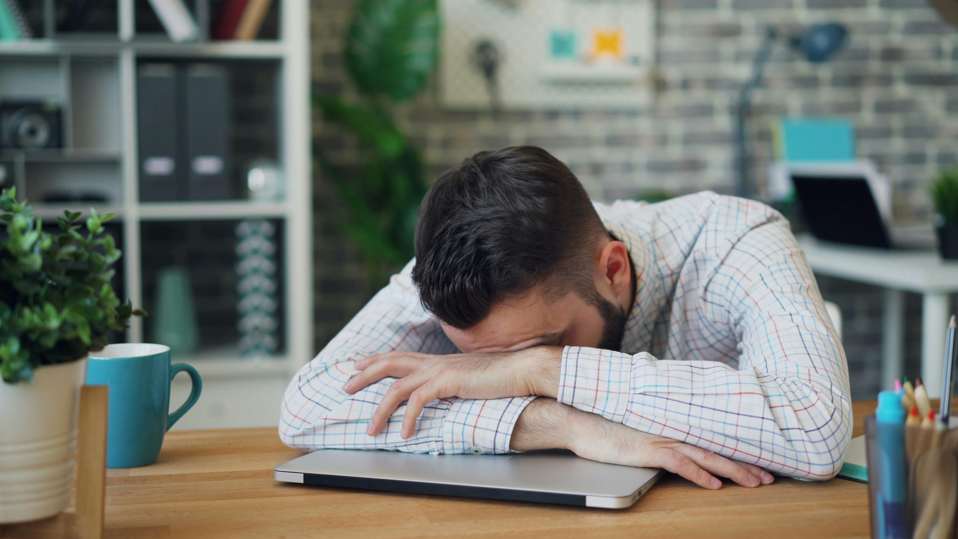 A man feeling tired of working, he fall asleep on his laptop