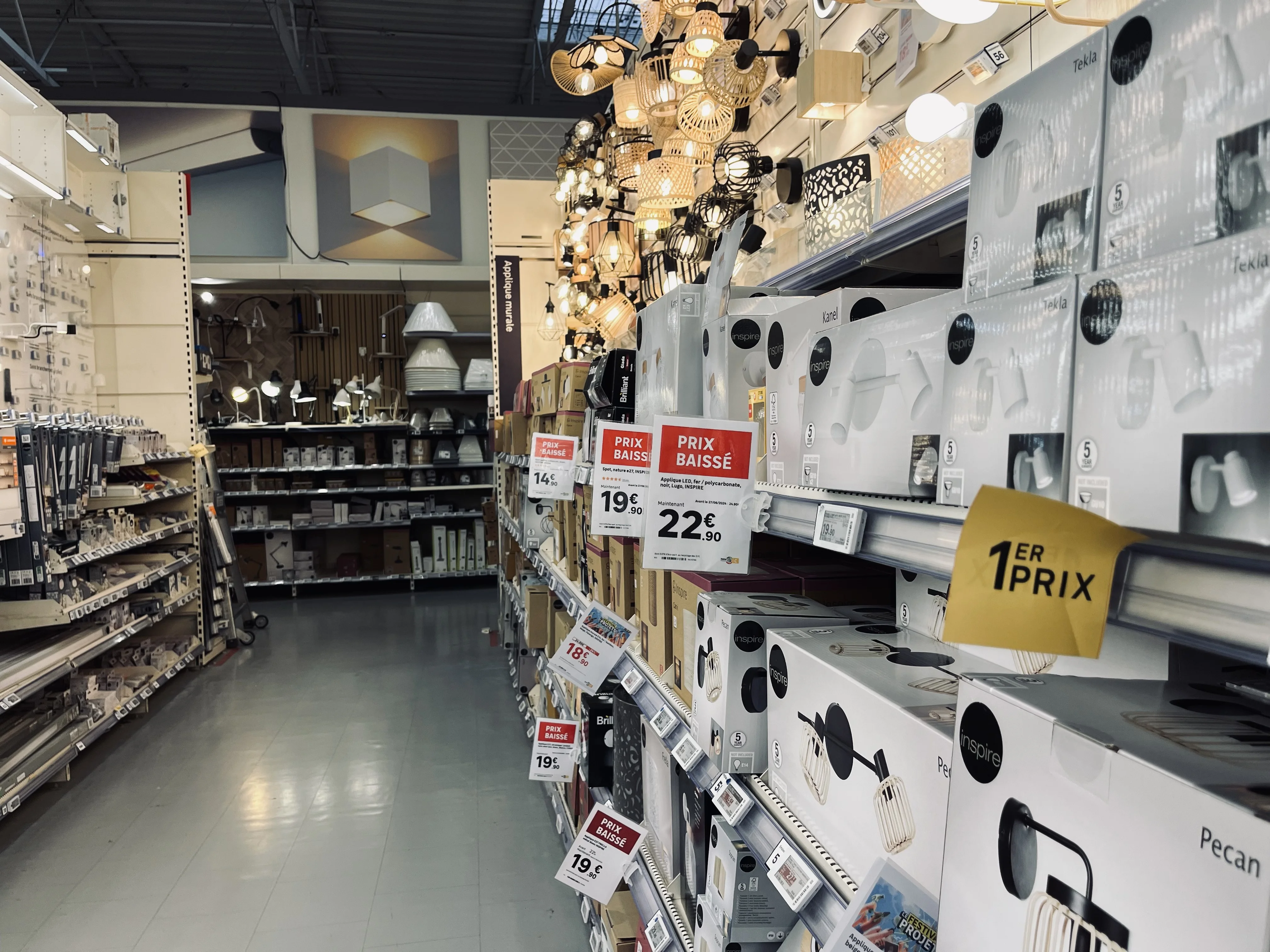 Allée de magasin avec affiches et étiquettes de prix suspendues au-dessus des rayons