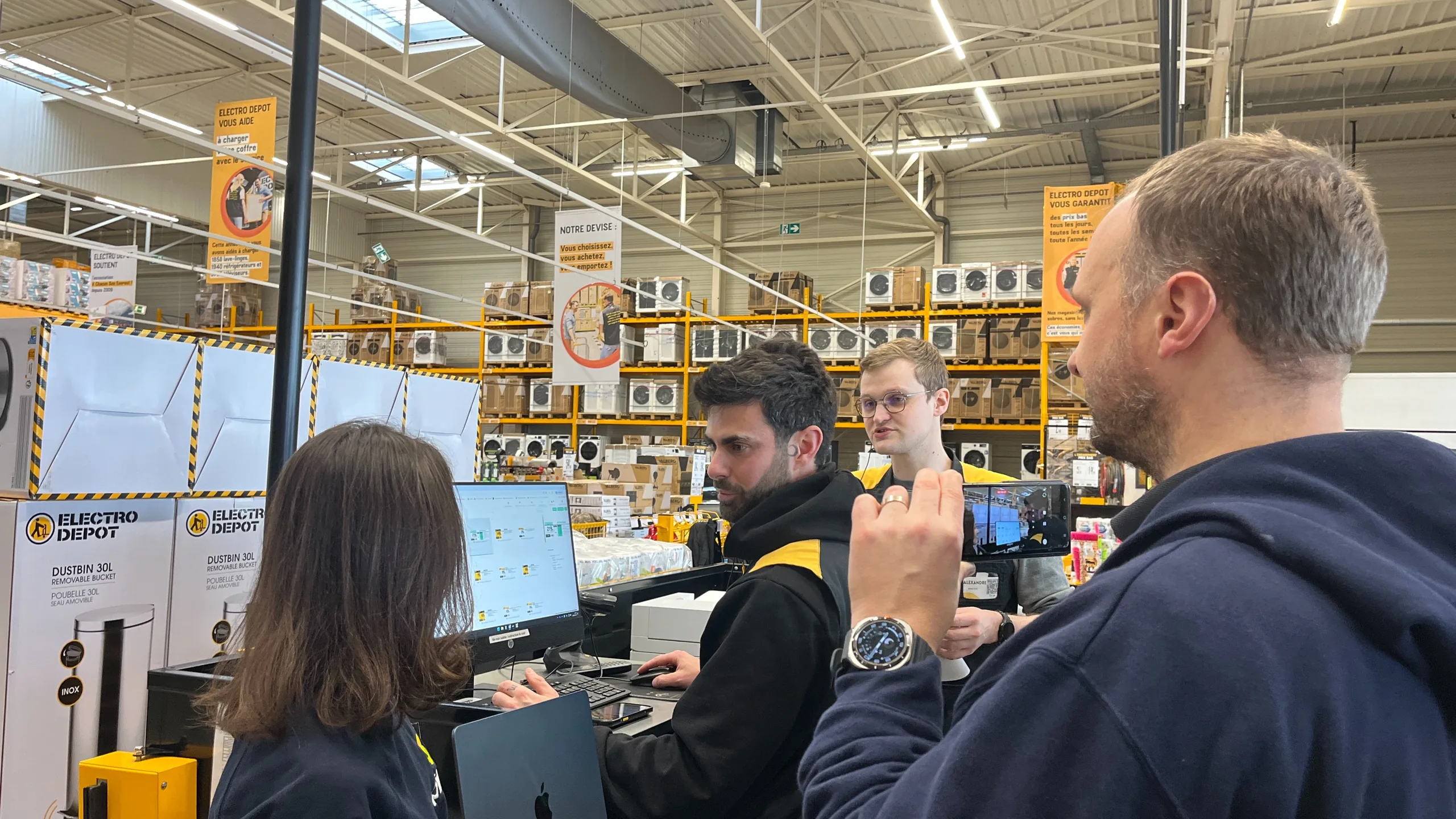 Équipe en magasin réunie autour d'un poste informatique pour la création des affichages