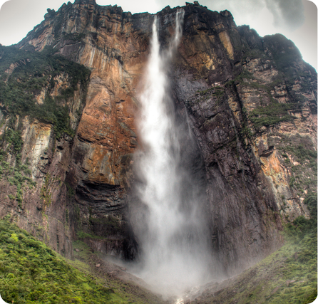 Ángel Falls with a tall narrow waterfall dropping from a high cliff into forest below
