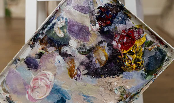 Close-up of a painter's palette covered with various mixed oil paints in different colors.