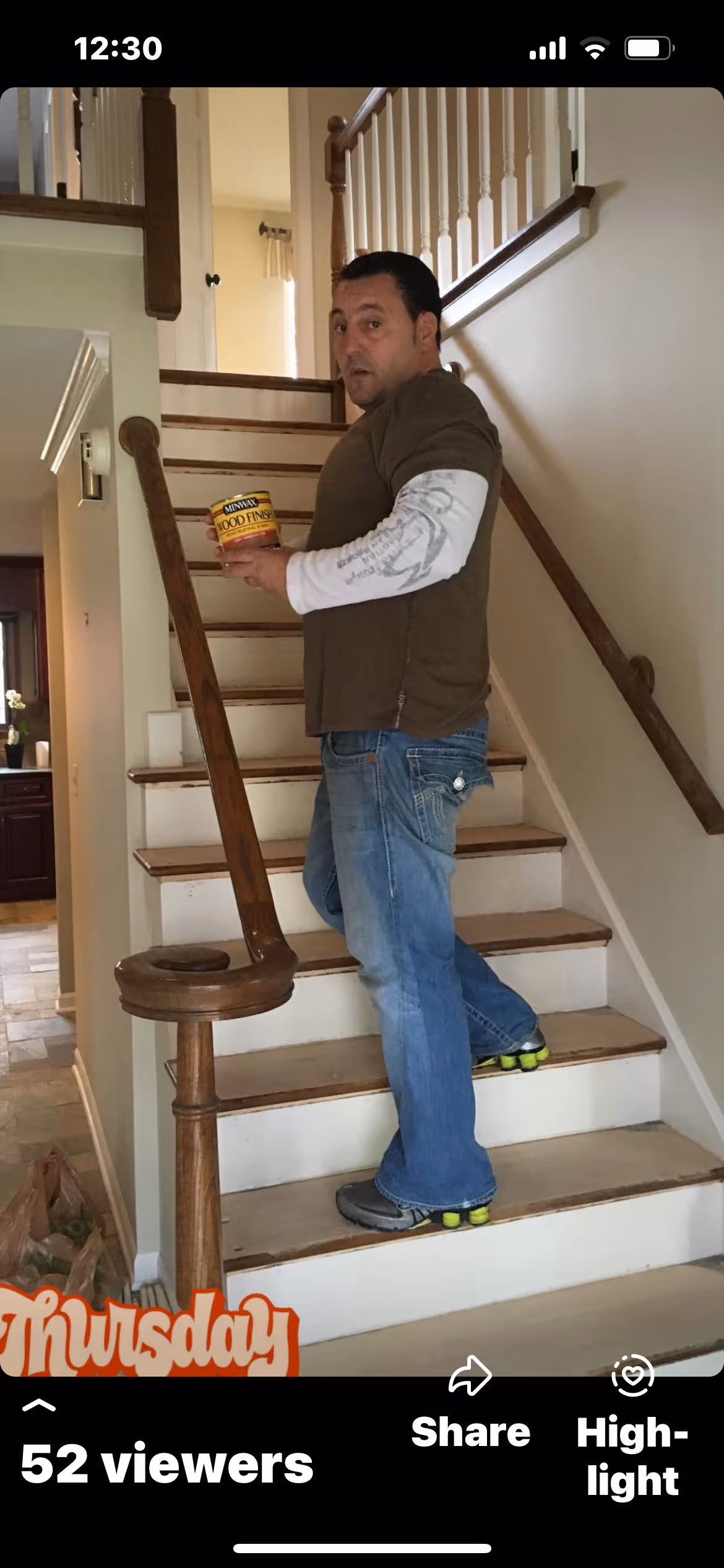 Man on staircase holding a can of Minwax Wood Finish, looking towards the camera.