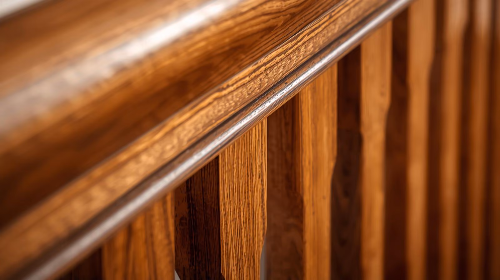 Close-up of polished hardwood railing and balusters showing wood grain details.