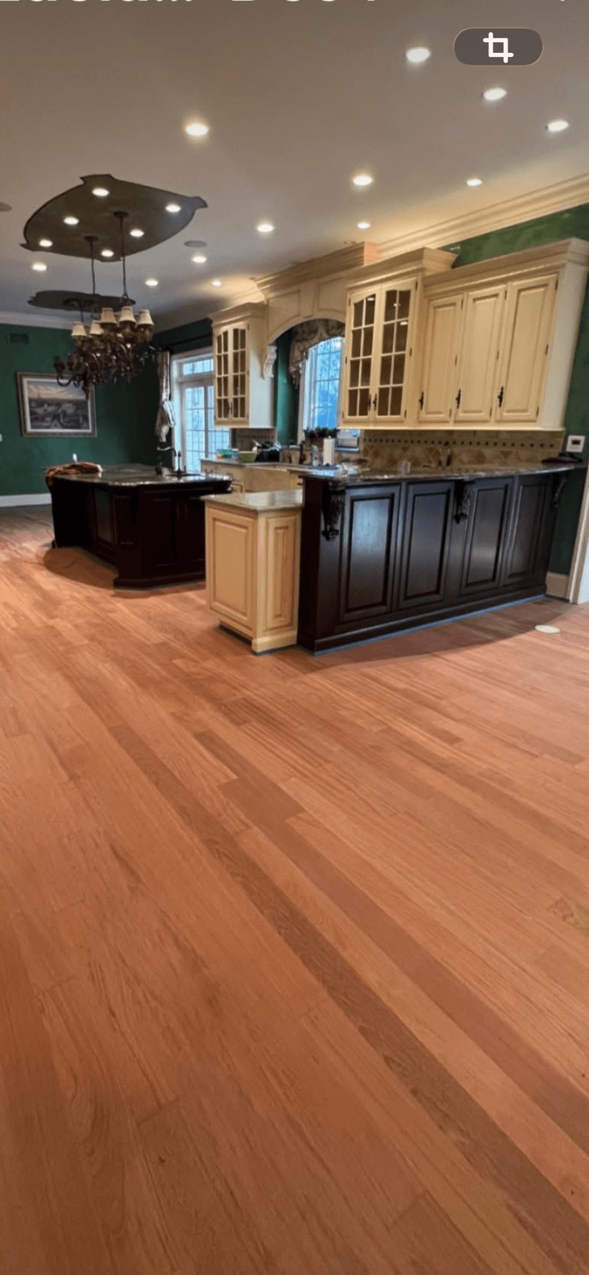 Shiny finished hardwood floor in a kitchen with wooden cabinets and a center island.