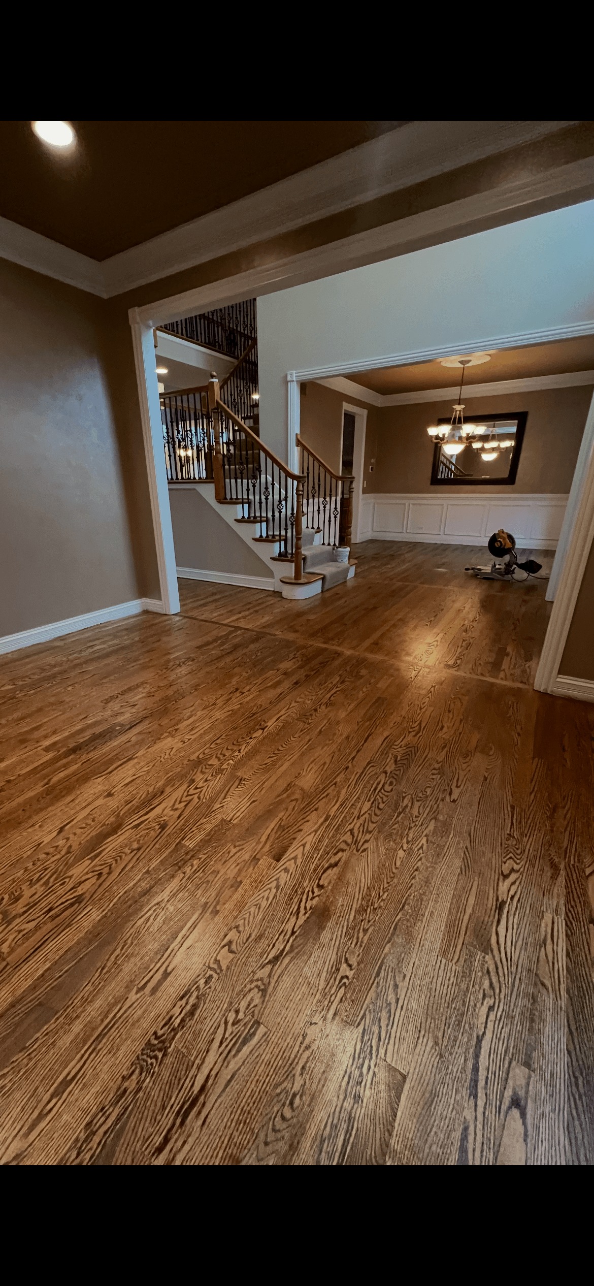 Man operating floor polishing machine on hardwood floor in kitchen with brown cabinets.