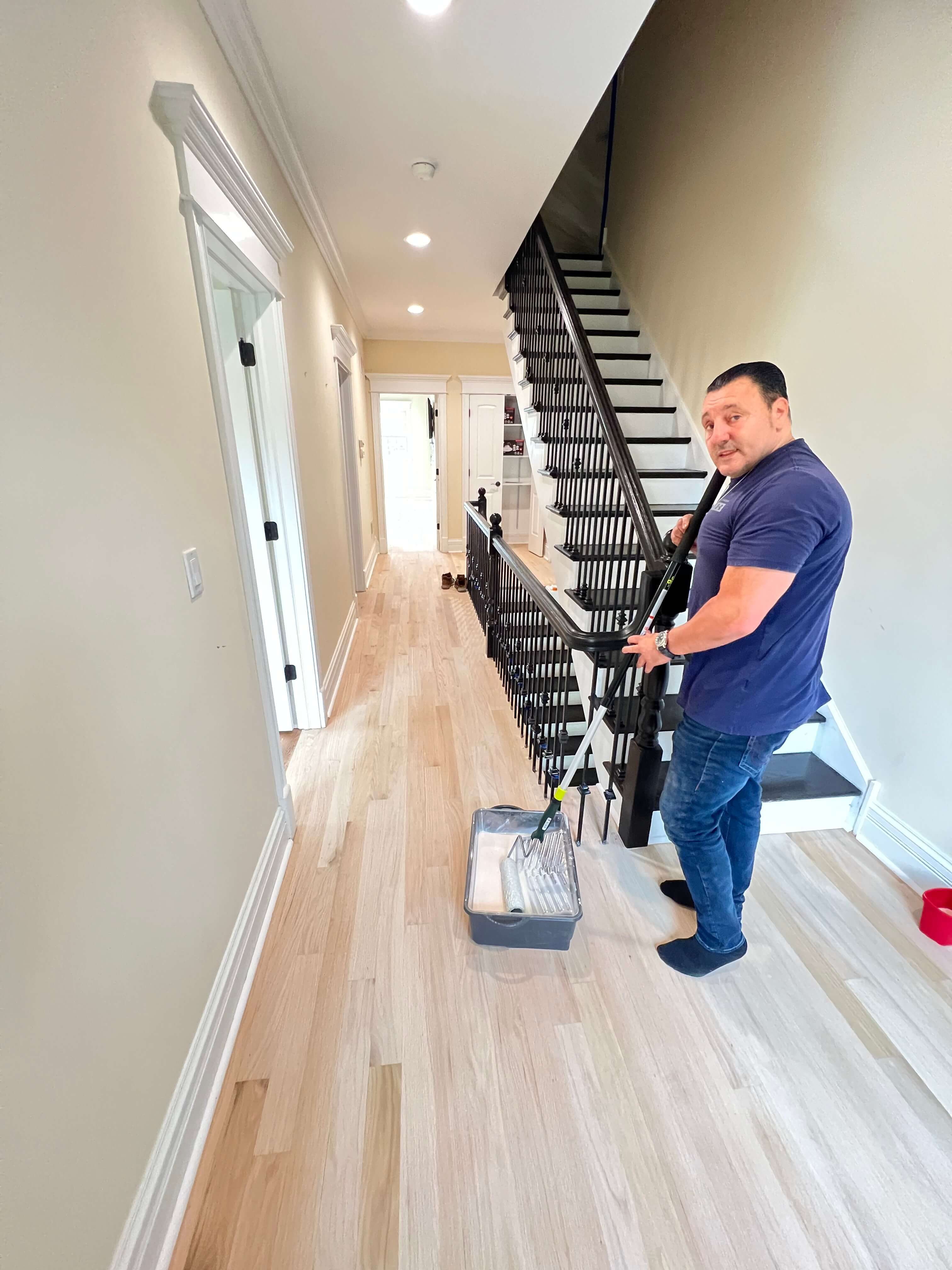 Man operating floor polishing machine on hardwood floor in kitchen with brown cabinets.