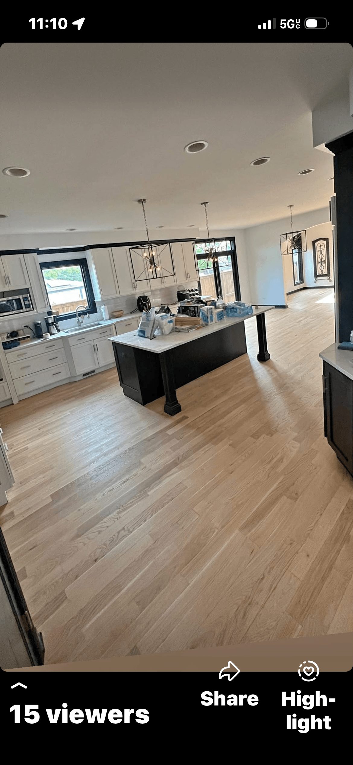 Empty modern room with light wood floor, dark kitchen island, staircase, and blue LED ceiling lights.