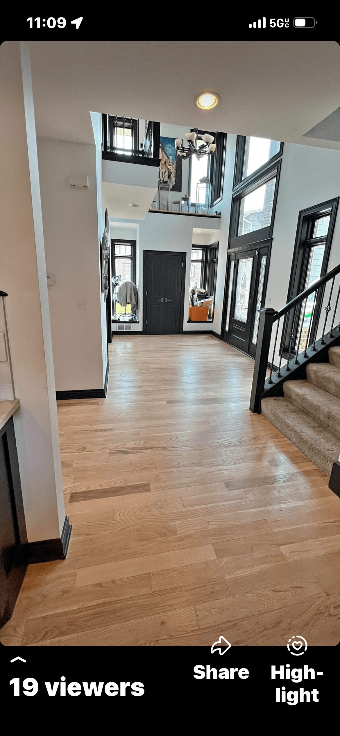 Man using floor buffer to polish wooden floor in a large kitchen with dark cabinets.