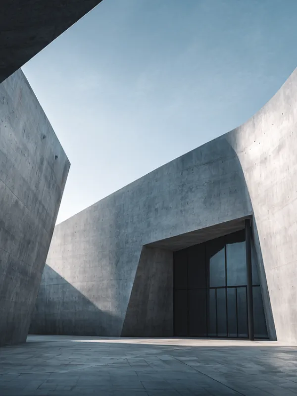 Modern concrete building with sharp angles and large glass entrance under a clear blue sky.