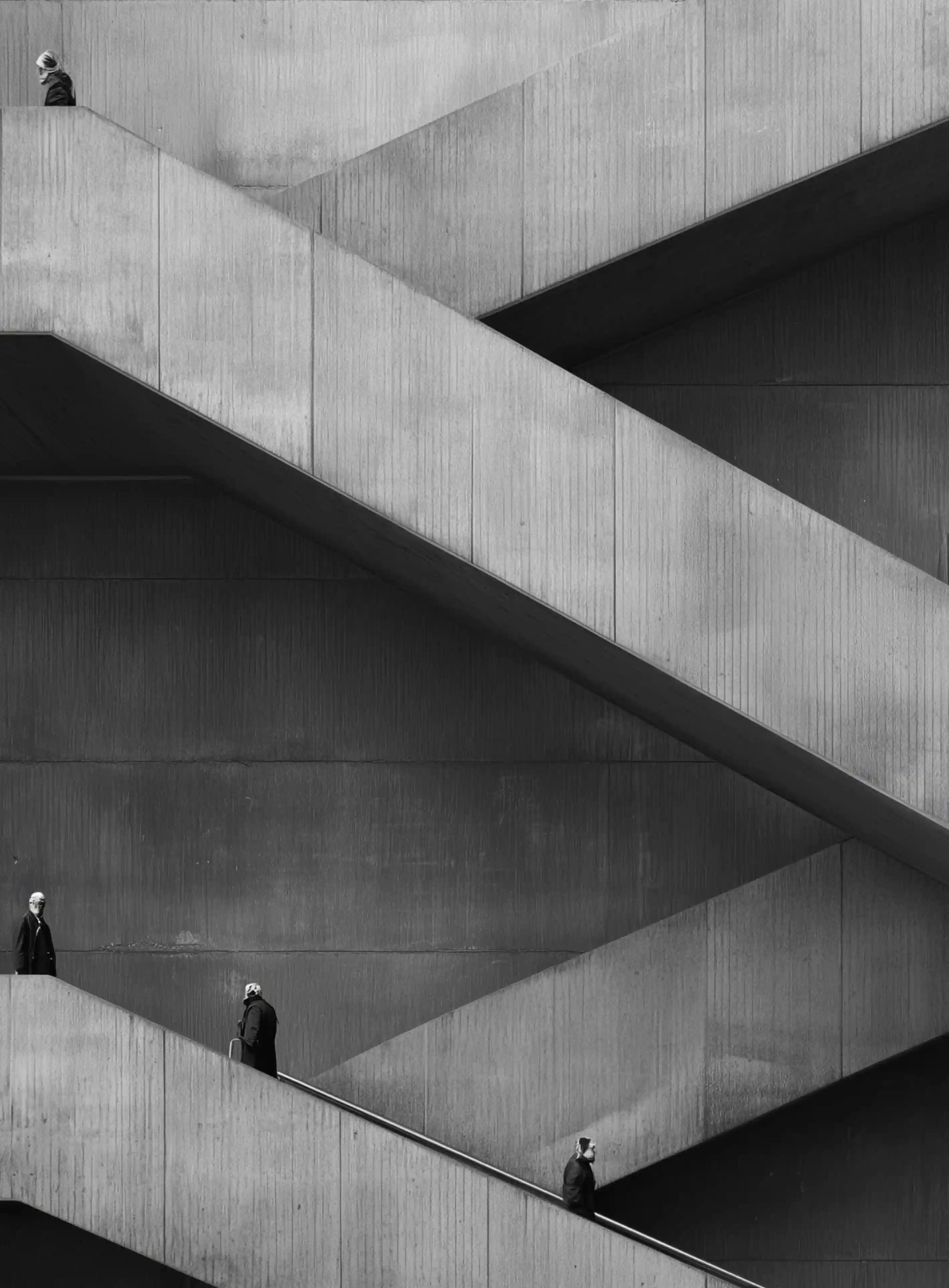 Black and white photo of four people on intersecting outdoor concrete staircases.