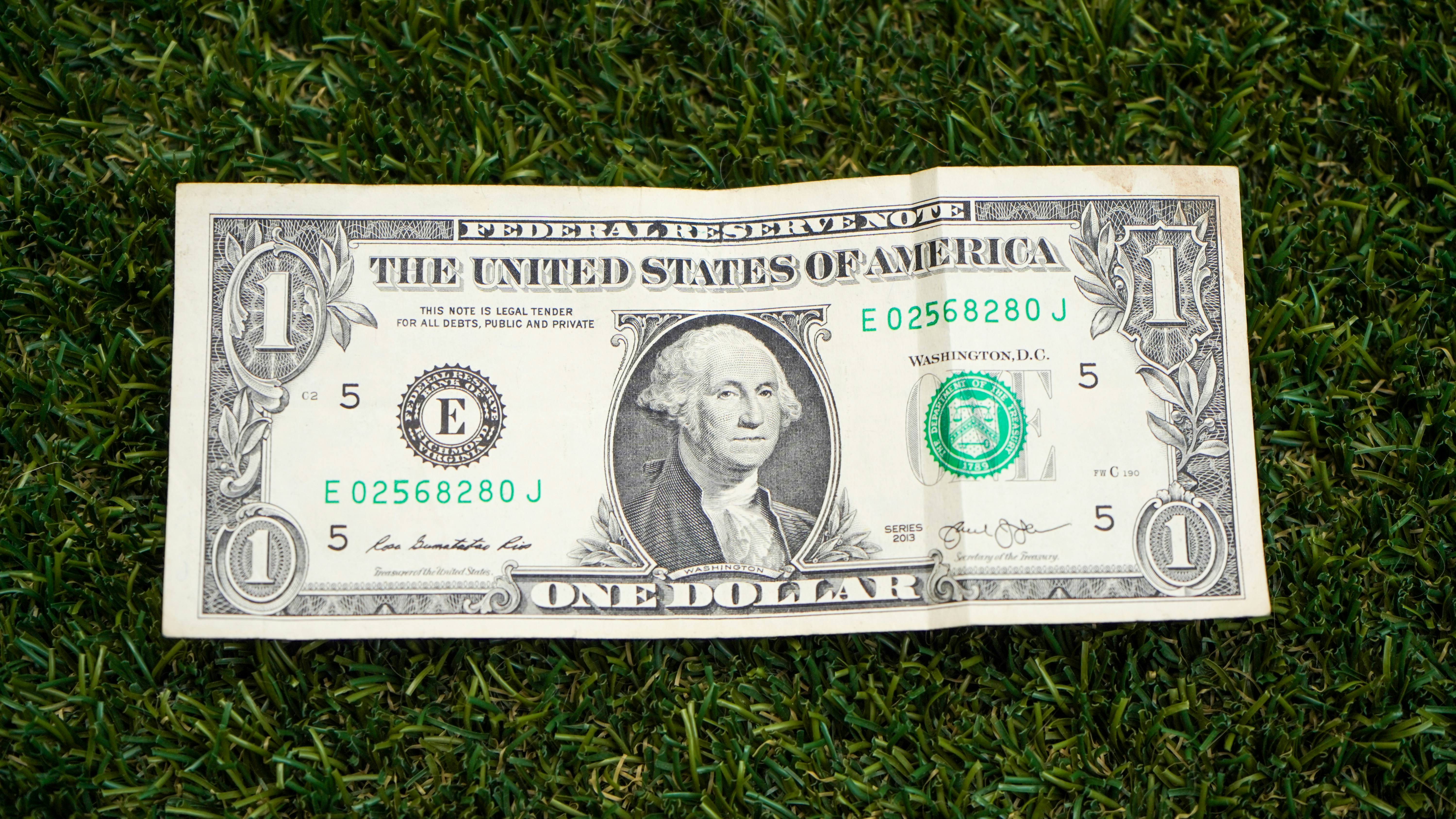 `Ein-Dollar-Schein auf grünem Gras – US-Dollar Geldschein Nahaufnahme`