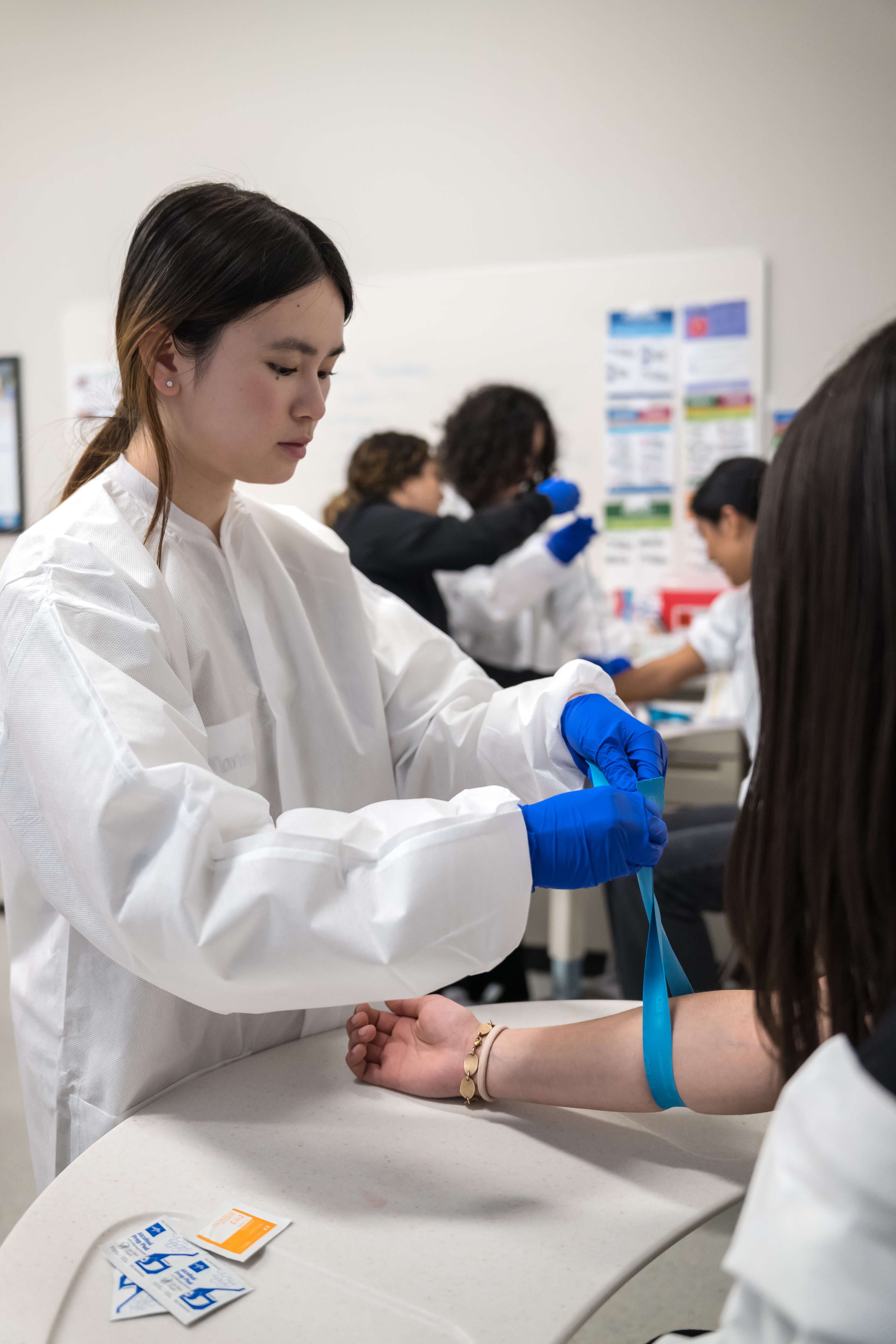 Student wearing gloves and protective gear practicing a healthcare skill in class.