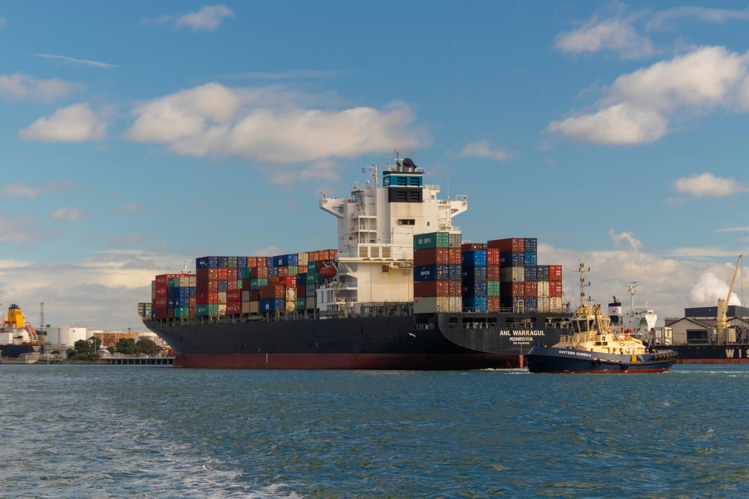 Container ship and tugboat moving through a harbor as part of a maritime career pathway image.
