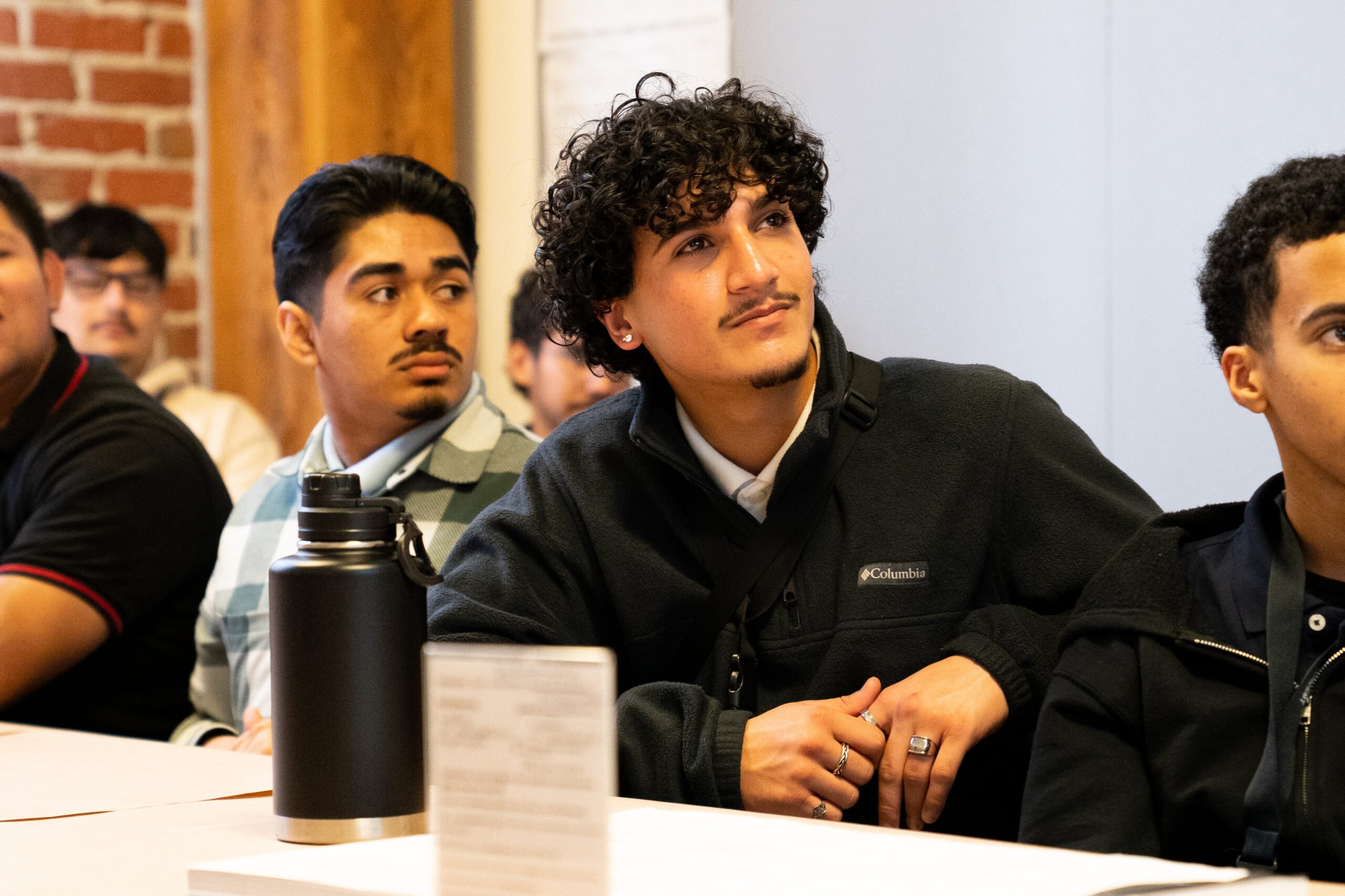A group of male students seated at a table participating in a classroom-based healthcare career training session