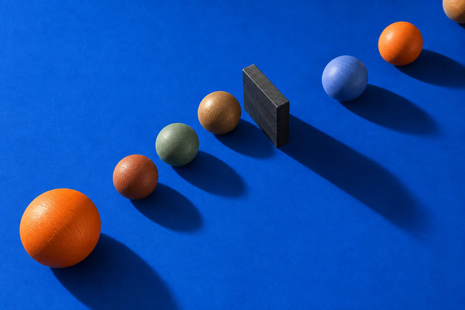 Colorful wooden spheres form a queue interrupted by a dark block.