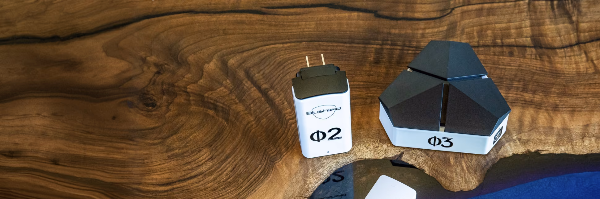 Two electronic devices labeled Phi 2 and Phi 3 on a polished wooden surface.