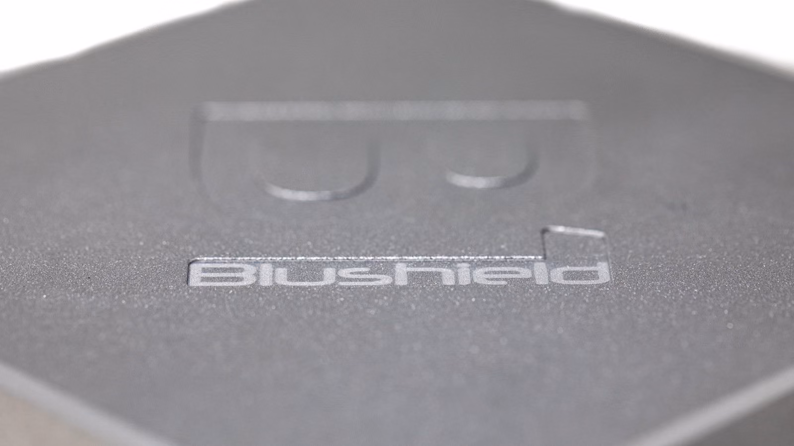 Close-up of matte metallic surface with the word Blushield embossed on it.
