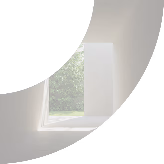 Minimalist modern hallway with concrete walls opening to a garden with green foliage and sunlight.
