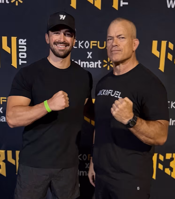 Two men in black shirts posing with clenched fists in front of a backdrop featuring logos for 4F TOUR, JackFuel, and Walmart.