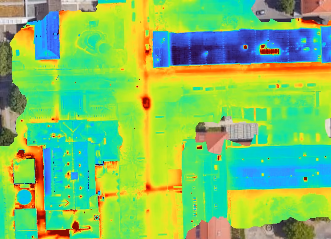 Thermisches Luftbild von Gebäuden mit Farbkodierung für Temperaturunterschiede, weiße Hotspots für Wärmelecks.