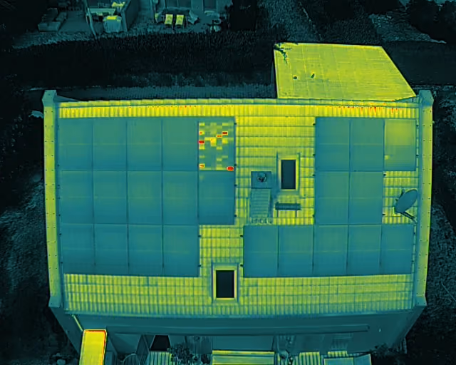 Thermisches Bild eines Hauses mit Solarmodulen auf dem Dach und einigen defekten Modulen sichtbar.