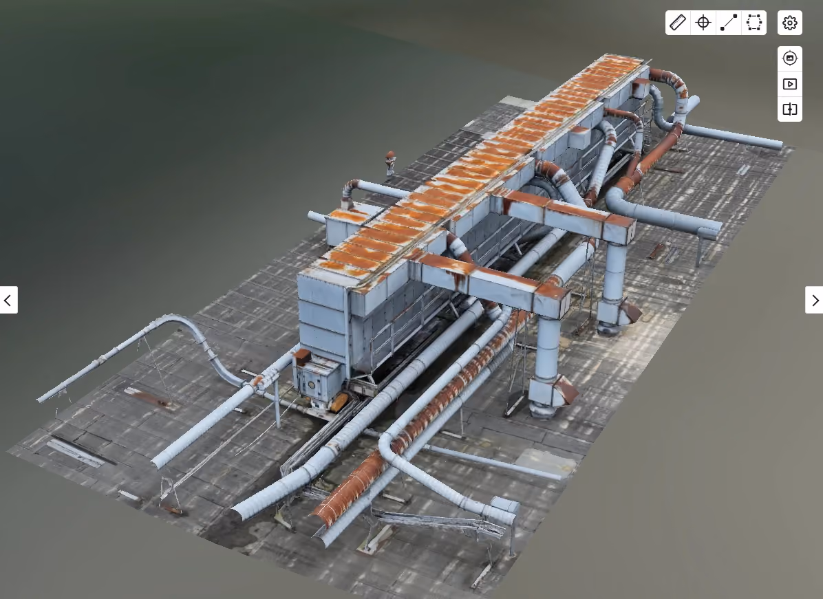 Modell einer rostigen Industrieanlage mit mehreren Rohren und Metallstrukturen auf einem Betonboden.