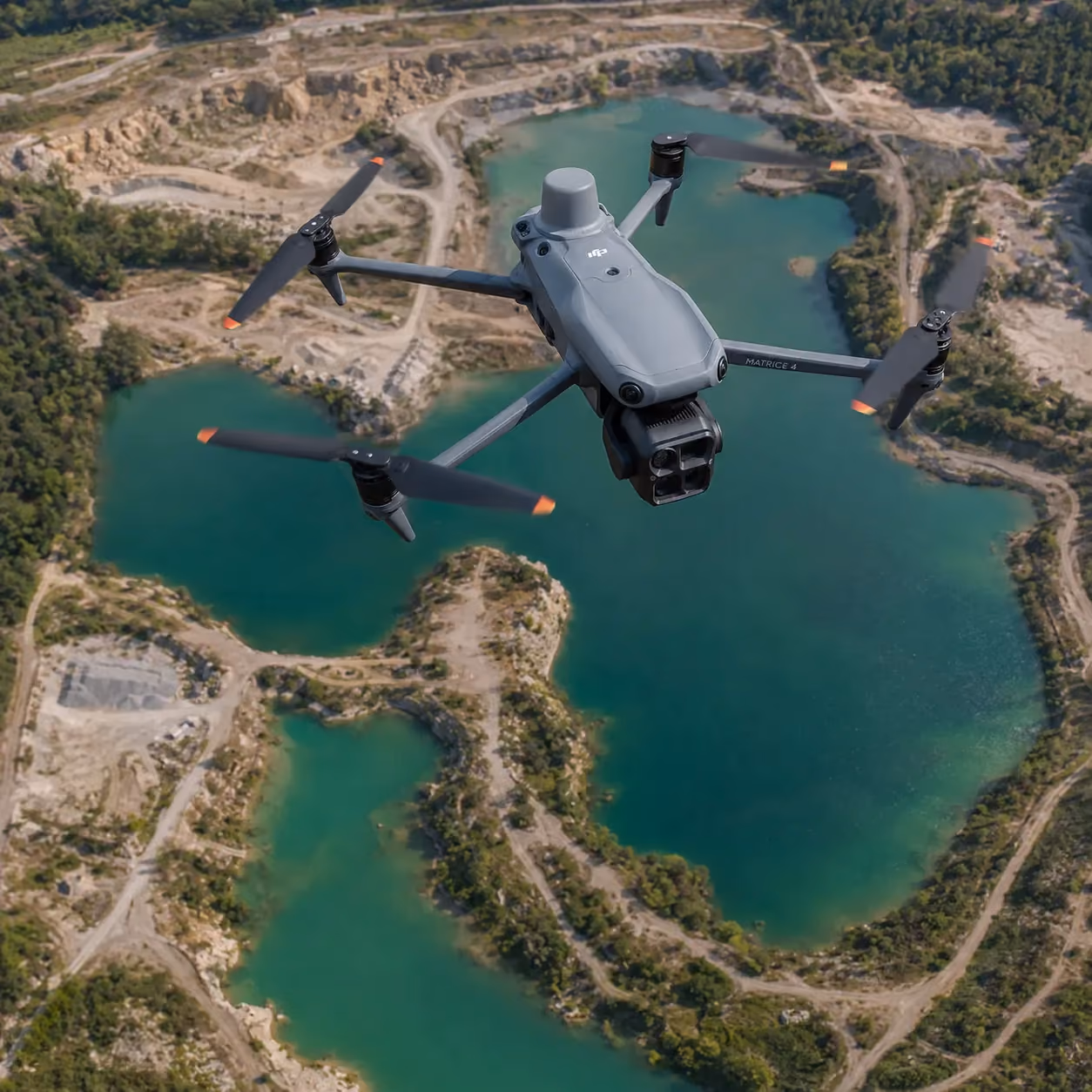 Graue Drohne fliegt über einen See mit grünen Inseln und bewaldeten Ufern.