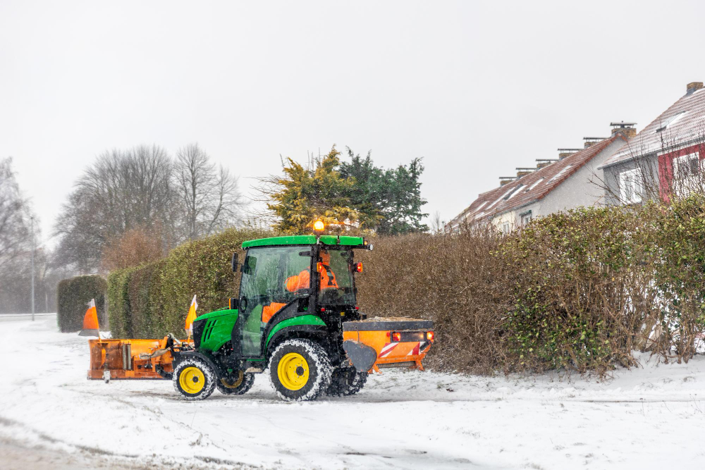 Kleiner Traktor räumt Schnee in Wohngebiet während Schneefall