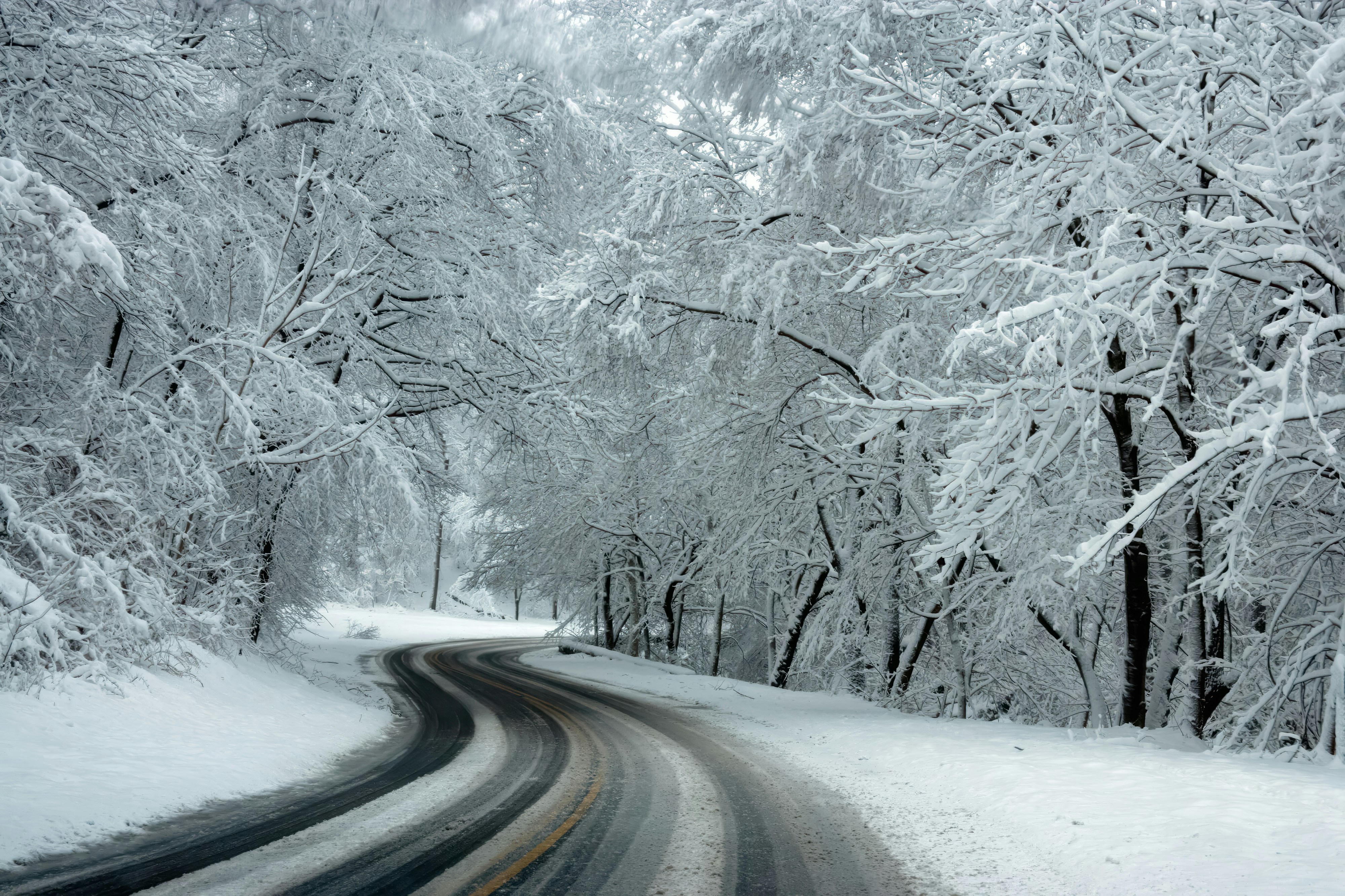 Kurvenreiche Winterstraße durch schneebedeckten Wald – vereiste Fahrbahn Winterlandschaft