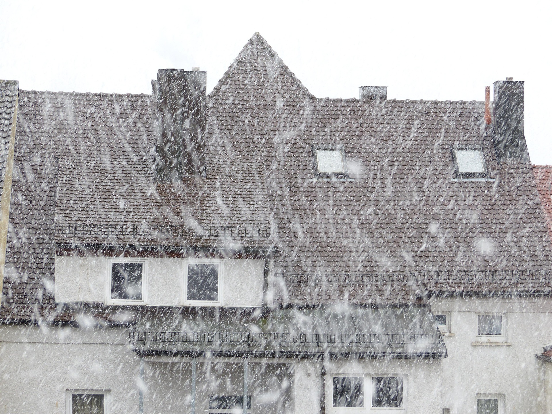 Dichtes Schneetreiben vor einem Wohnhaus mit Satteldach und Dachgauben