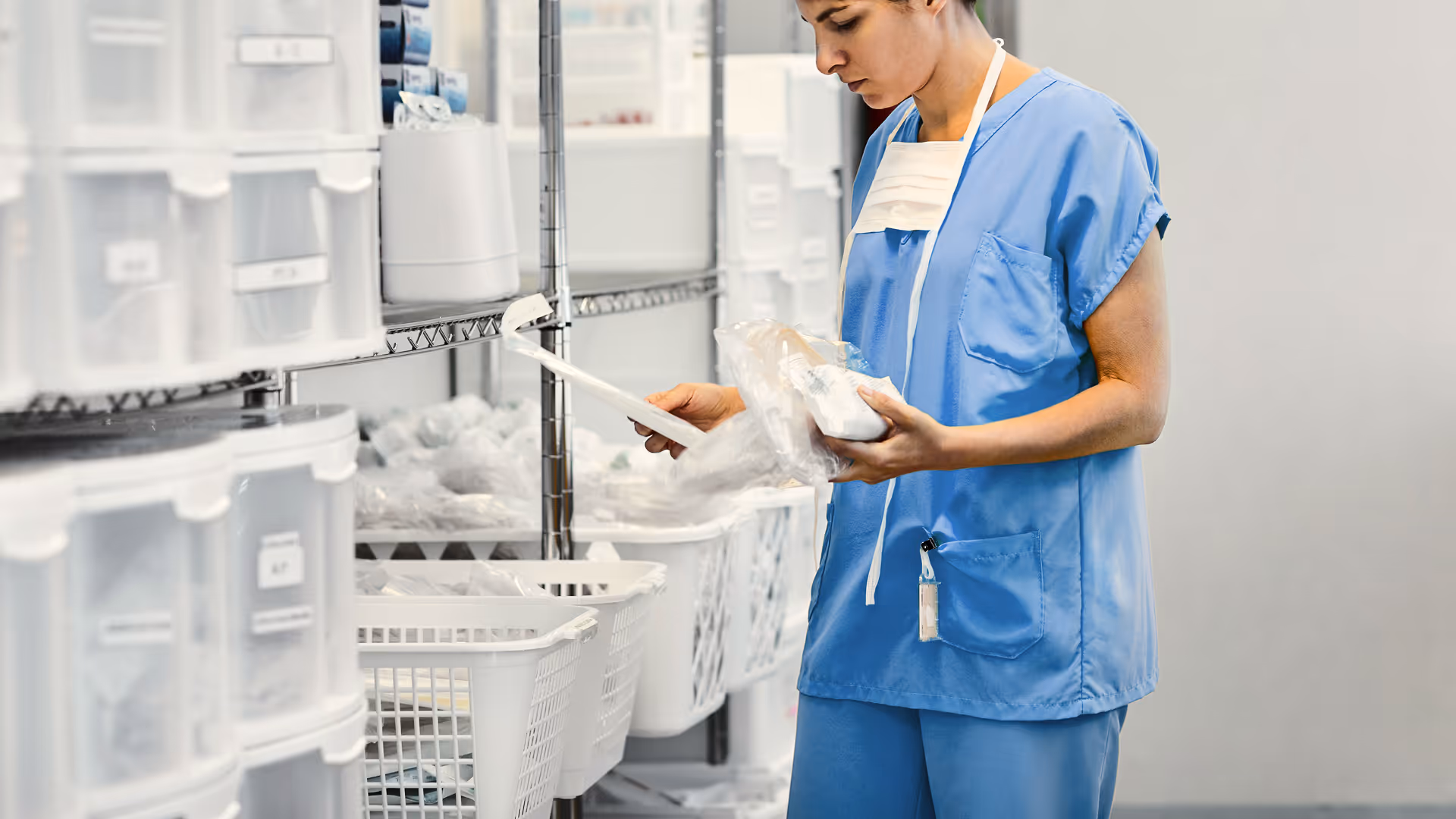 Healthcare professional in blue scrubs checking medical supplies in a well-organized storage room.