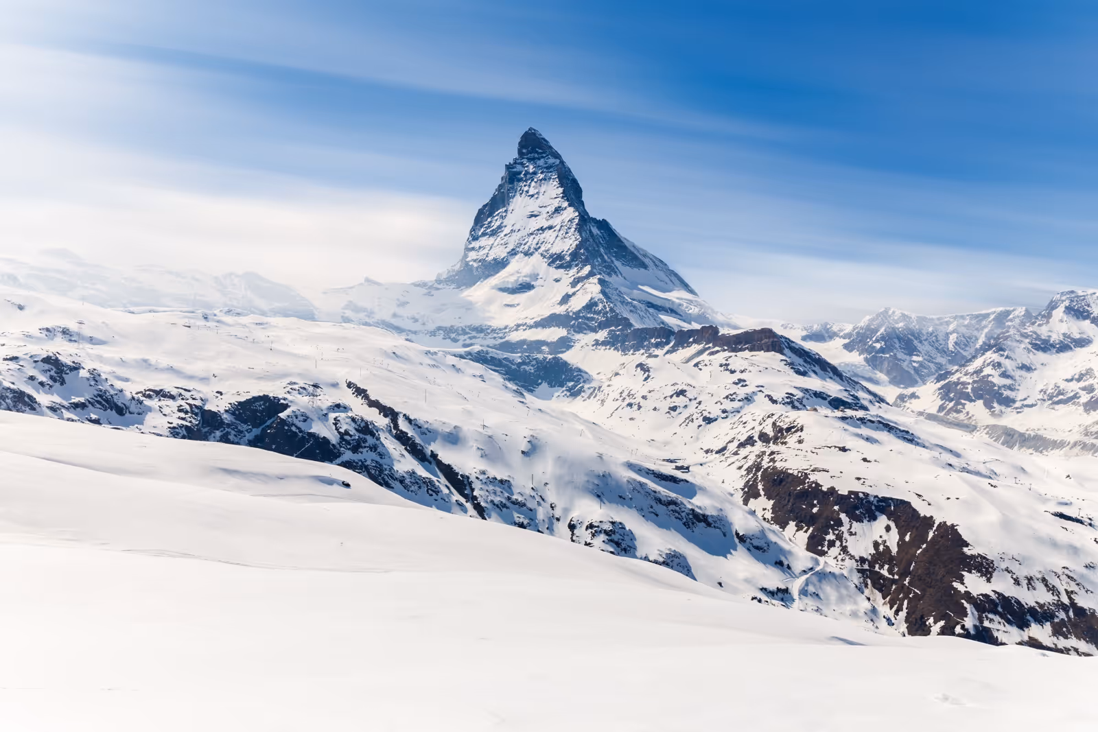 Snow-covered Matterhorn mountain peak against a clear blue sky in the Swiss Alps.