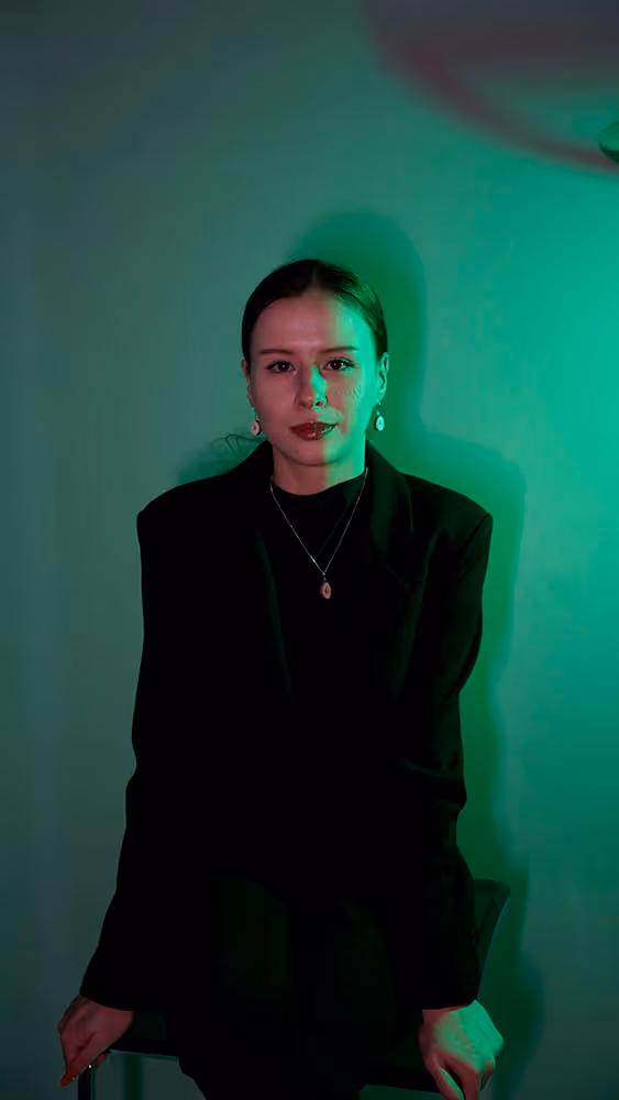 Angelina, Co-founder and Experience Designer at Guidance DMC, looking at the camera against a green neon lit background
