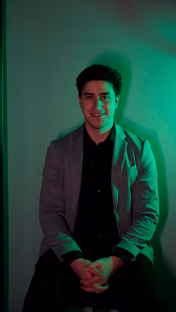 Ross, Co-founder and Customer Happiness Lead at Guidance DMC, smiling against a green neon lit background