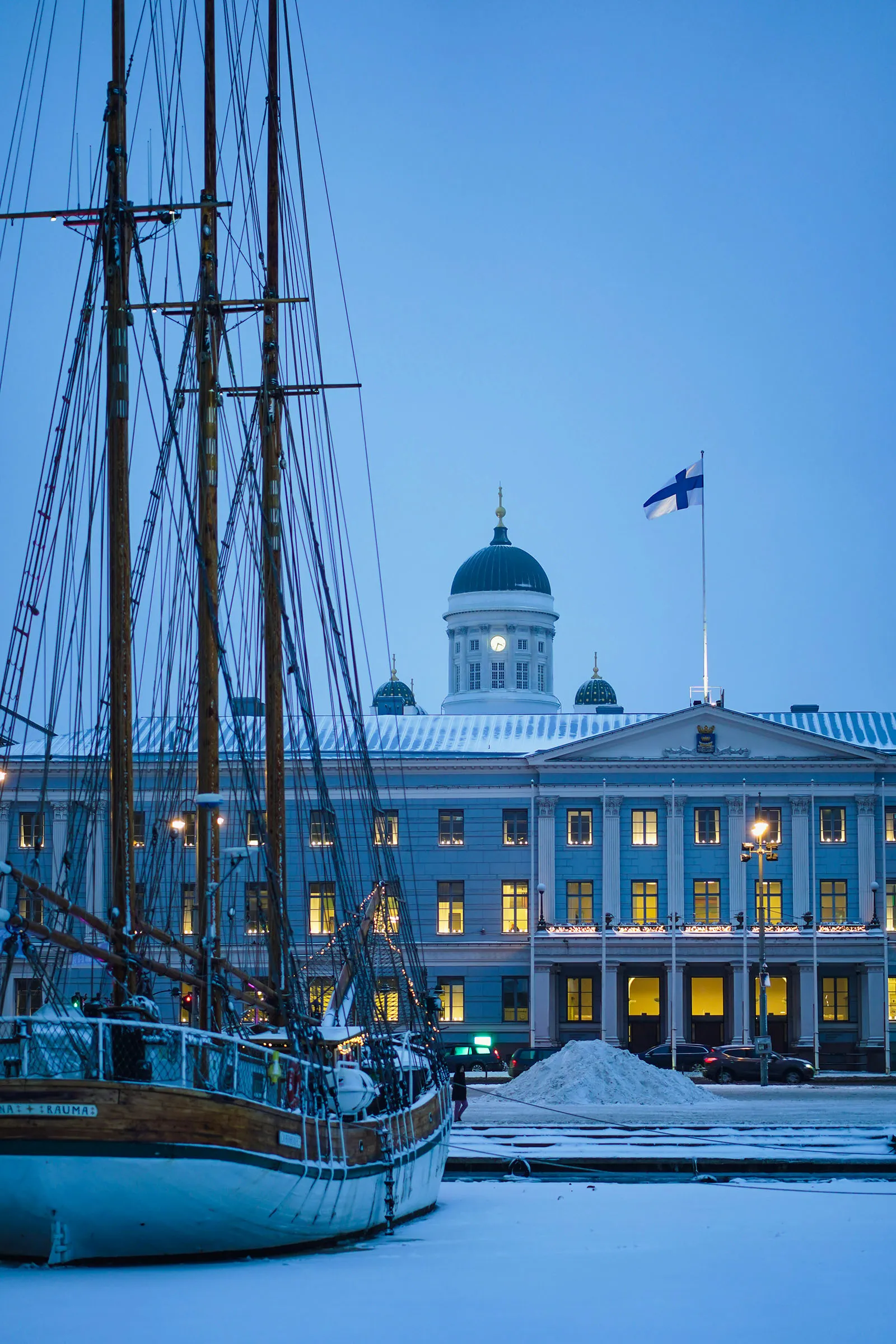 Tall ship moored in the frozen harbour by Helsinki City Hall at dusk