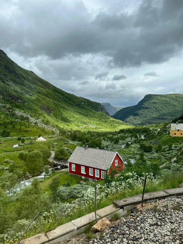 Red wooden house in a green Norwegian mountain valley