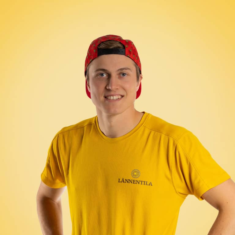 Nuori mies hymyilee kameralle, yllään keltainen t-paita ja kuviollinen punainen lippalakki takaperin. T-paidan rinnassa on LÄNNENTILA-logo. Tausta on yksivärinen keltainen.