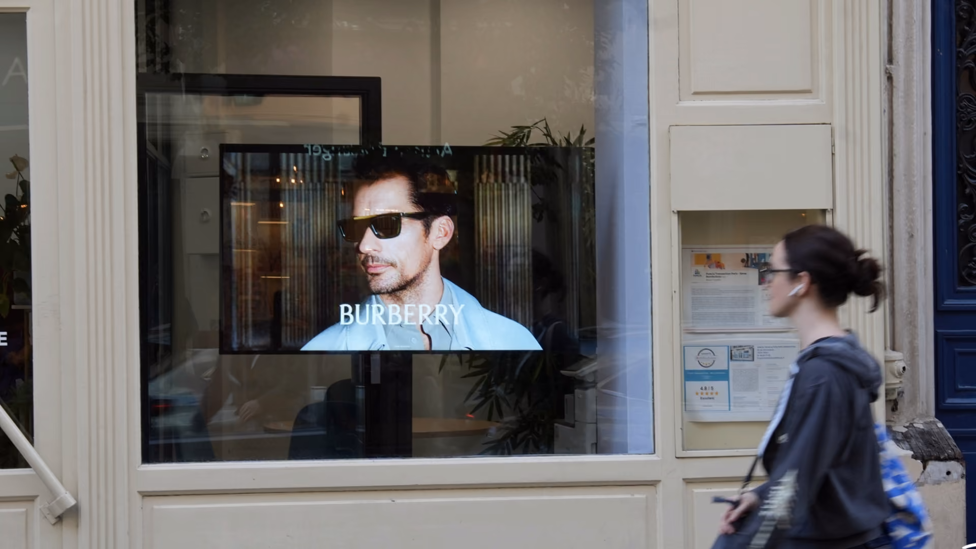 Une vitrine avec un écran montrant un homme portant des lunettes de soleil et le logo Burberry.