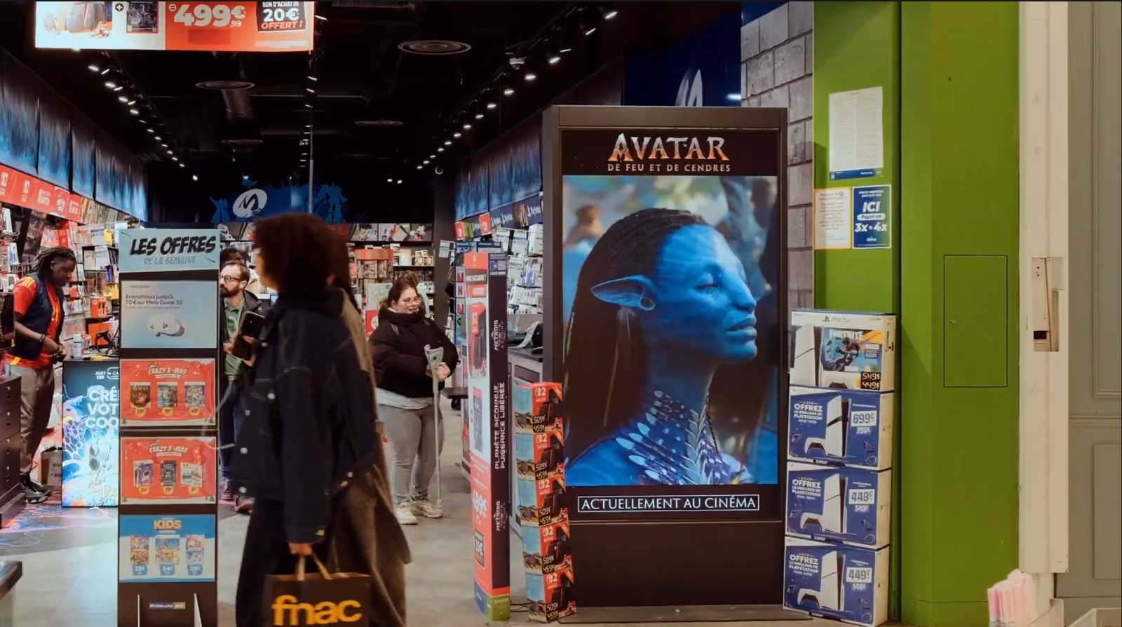 Intérieur d'un magasin avec des clients et une affiche numérique d'Avatar: de feu et de cendres.