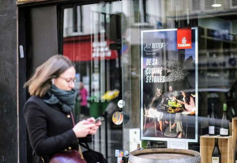 Passants captivés par un écran d’affichage numérique diffusant une publicité animée et impactante.