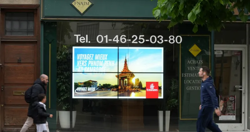 Un écran géant situé dans un lieu très fréquenté qui capte l'attention d'un grand nombre de passants.