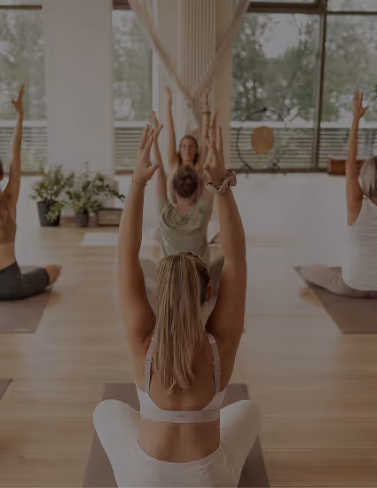 Yogagruppe mit erhobenen Armen im Studio von Nalu Yoga Rostock – Link zu den Kursangeboten
