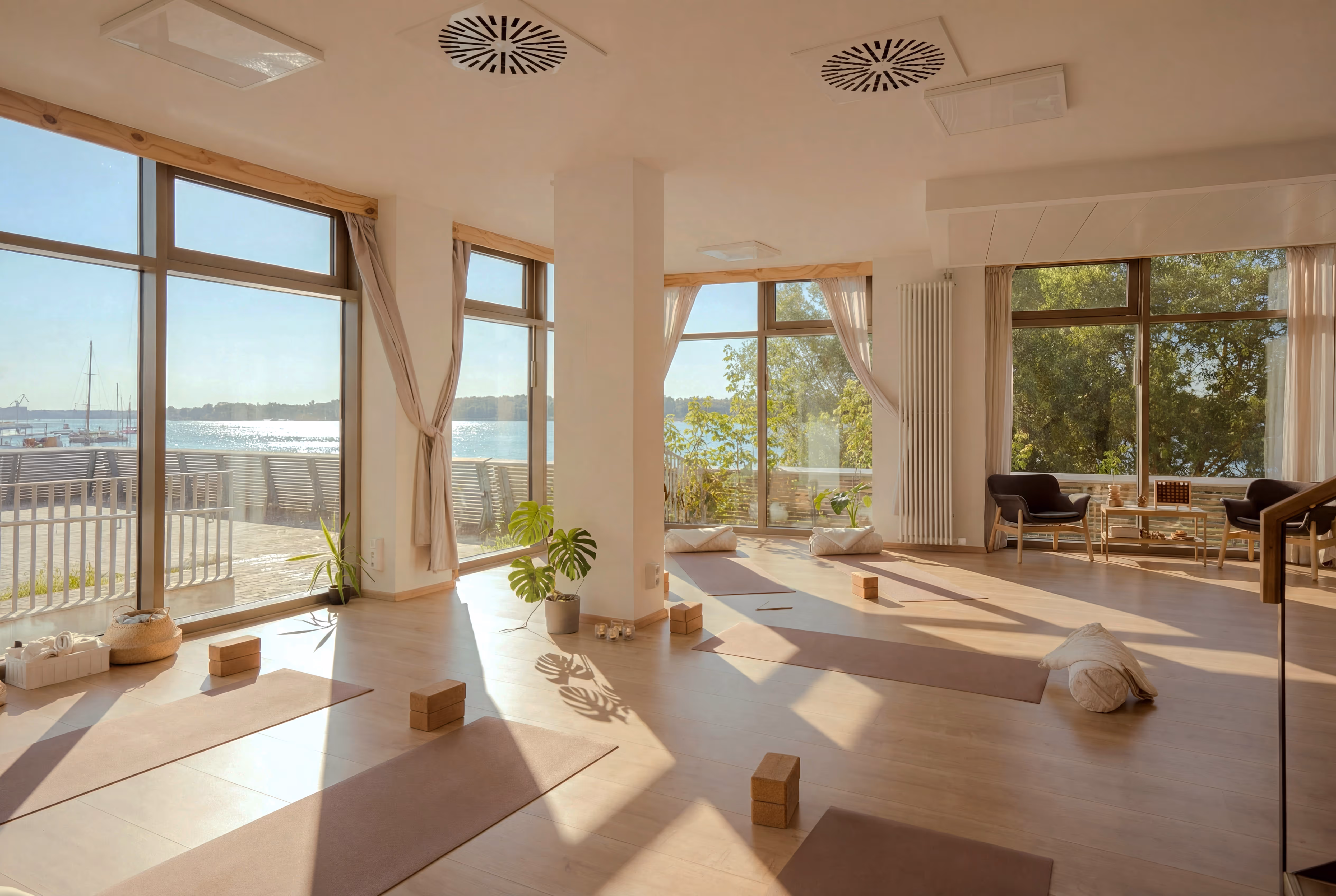 Heller Yogaraum mit großen Fenstern und Blick auf die Warnow im Nalu Yoga Studio Rostock als Hero-Bild der 1:1 Yoga Seite