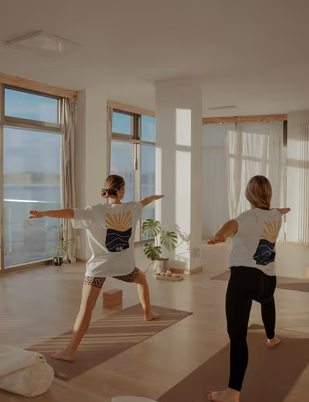 Zwei Frauen üben Yoga gemeinsam im nalu Yoga Studio Rostock mit Blick auf die Warnow