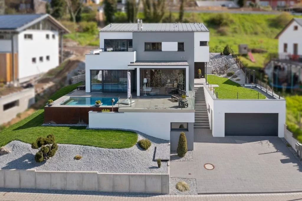 Modernes zweistöckiges Haus mit Pool, Terrasse, Garage und gepflegtem Garten mit Rasen und Kiesflächen.