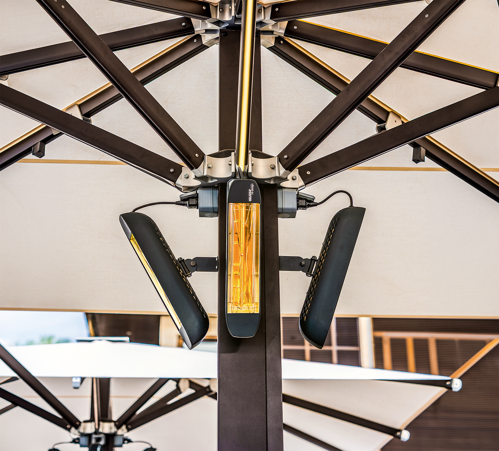 Calefactor eléctrico montado en el poste central de una sombrilla grande con estructura metálica.