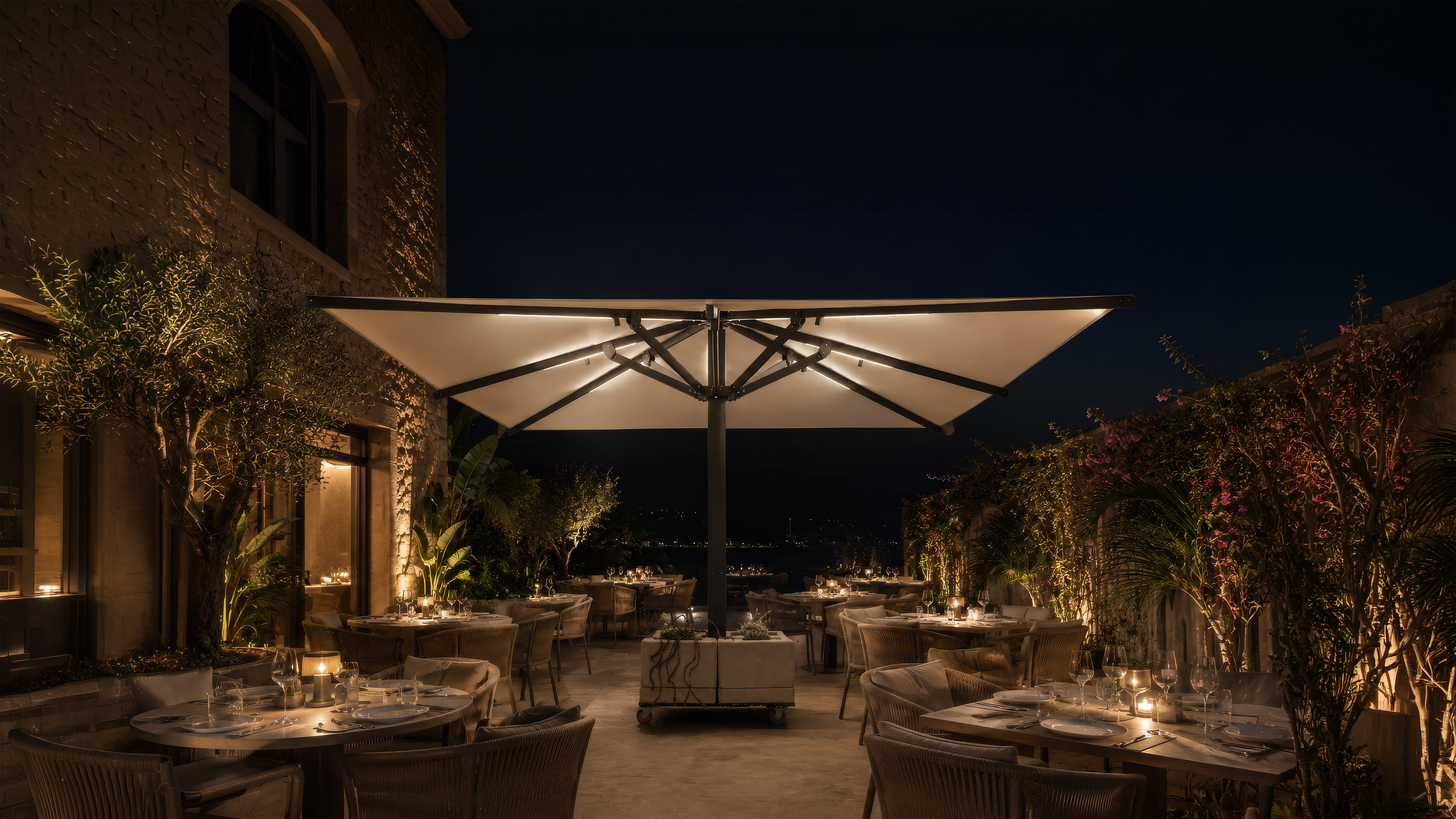 Terraza de restaurante con mesas de madera, sillas grises y un gran parasol negro.