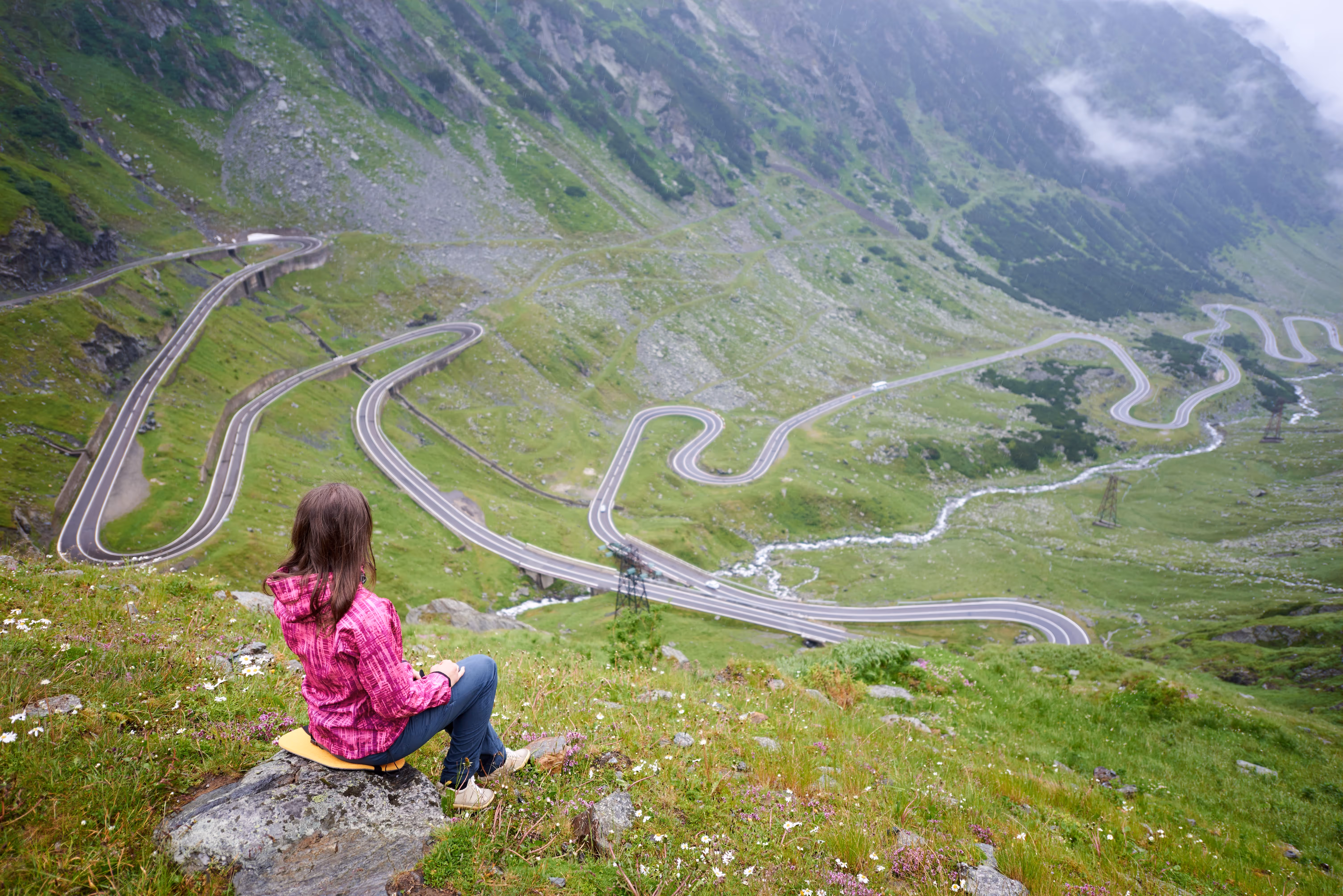 Turistă pe o stâncă admirând peisajul montan de pe Transfăgărășan